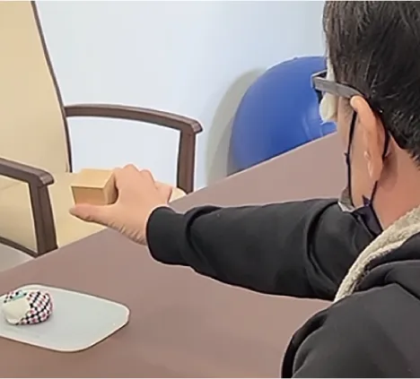 積み木を右手で掴む利用者。手の操作性を高めるトレーニング。