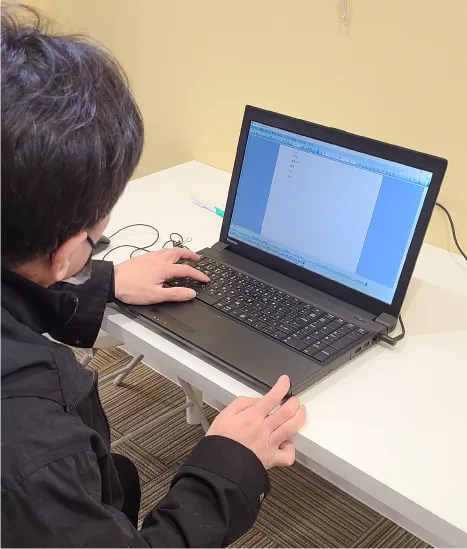 パソコンに向かいキーボードを打つ訓練をする利用者。